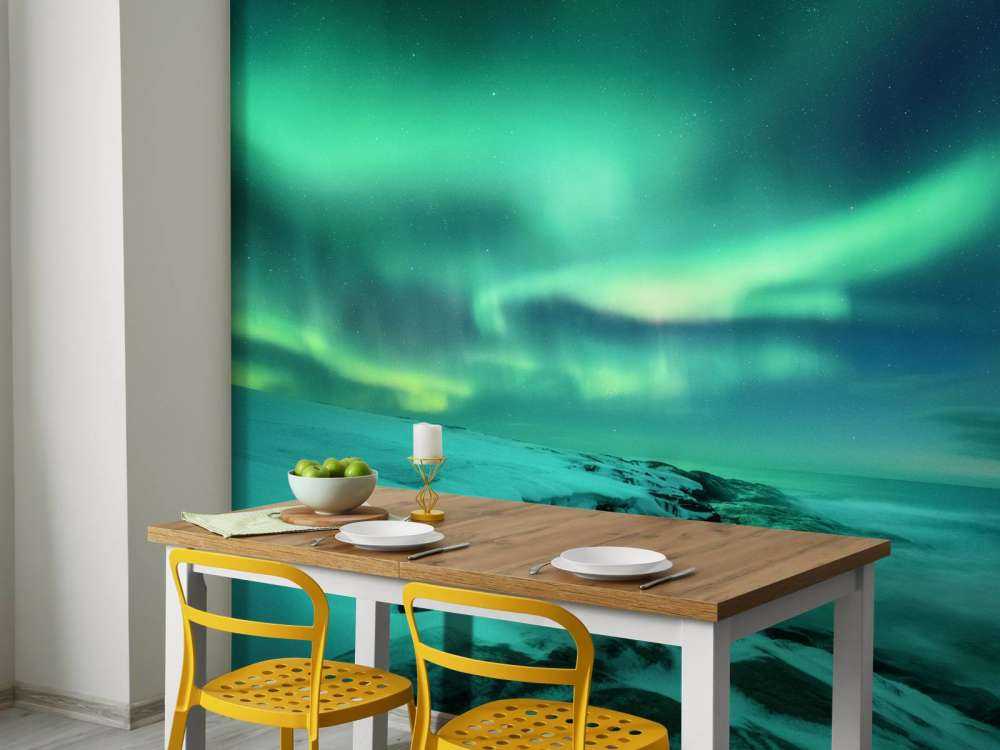 Grønt nordlys over snedækkede klipper